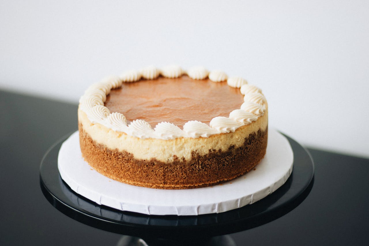 Elegant cheesecake with whipped topping, showcasing artisanal baking skills.
